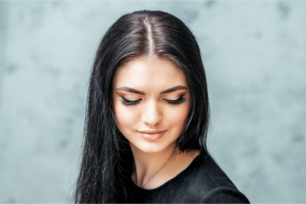 A woman showing difference between flat lash and classic lash.